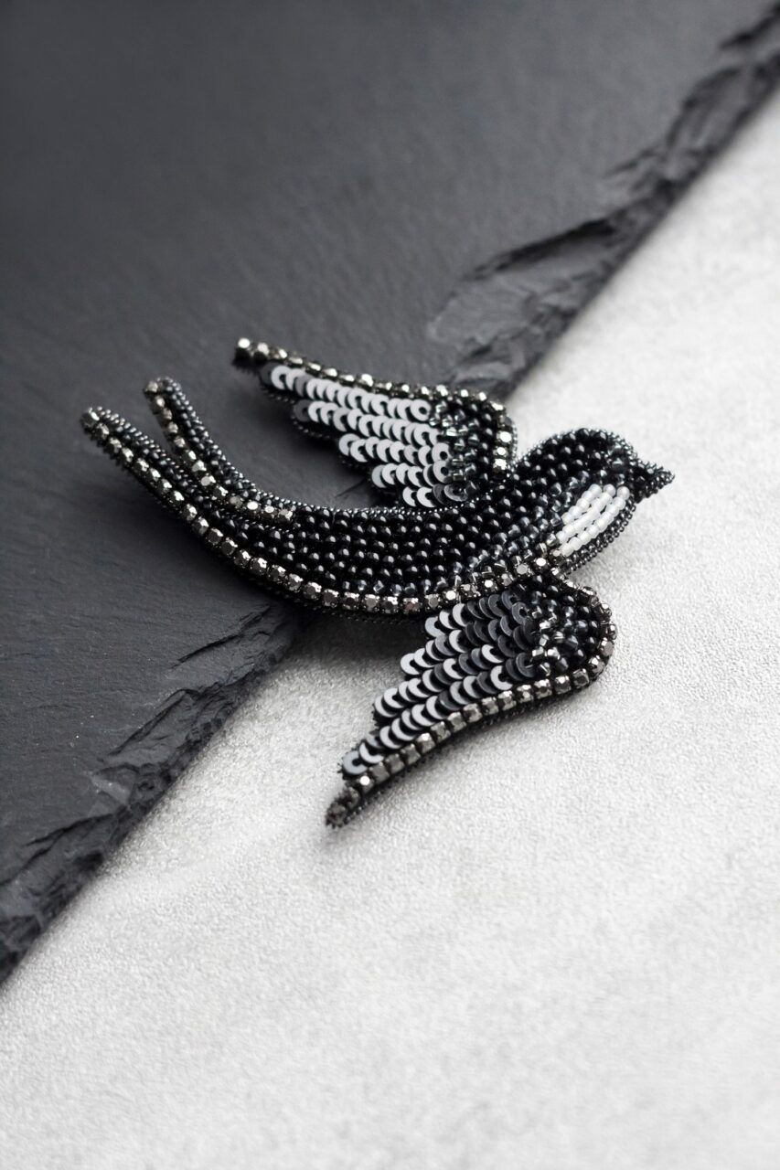 Broche en forme d’oiseau fixée sur un vêtement élégant.